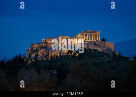 Atemberaubender Blick auf den beleuchteten Akropolis-Hügel und den Parthenon-Tempel in Athen, Griechenland bei Dämmerung. Die Akropolis gehört zum UNESCO-Weltkulturerbe. Stockfoto