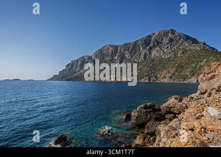 Blick auf die felsige Küste auf der zerklüfteten Insel Telendos in Griechenland an einem sonnigen Tag. Kopierbereich. Stockfoto