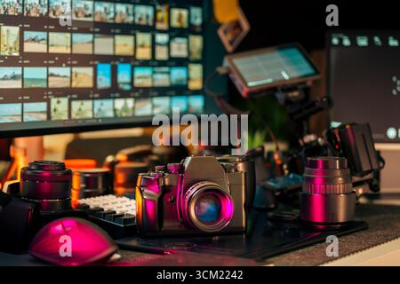 Creative Video Editing Desk Retro Kamera Objektiv Monitor Setup mit Vintage-Kamera, mehreren Objektiven, modernen Videobearbeitungsbildschirmen und Profis Stockfoto