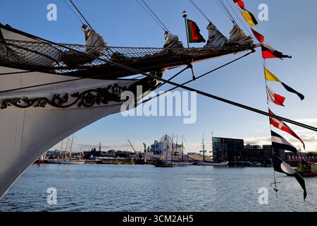 Detail eines großen Schiffsbogens mit Takelage, Fähnrich und Fähnrich, fotografiert bei Sail 2025 in Amsterdam, Niederlande, mit Blick auf das Hafenwasser. Stockfoto