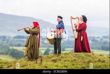 Von links nach rechts, Musiker in traditioneller Kleidung aus dem 15. Jahrhundert, Beck Laxton spielt einen Schal, Brad Chick spielt eine mittelalterliche Trommel und Jackie Phillips spielt eine bray Harfe während des Medieval Music in the Dales Festivals auf dem Gelände Bolton Castle in der Nähe von Leyburn, North Yorkshire. Das Festival findet in und um Bolton Castle statt, das 1399 von der adligen Familie Scrope erbaut wurde. Am Wochenende erwacht die Gegend mit Musik und lebendiger Geschichte zum Leben, da sie eine Gemeinschaft mittelalterlicher Musikbegeisterter zusammenbringt. Bilddatum: Sonntag, 14. September 2025. Stockfoto