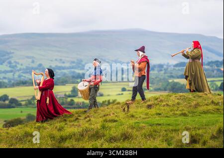 Von links nach rechts, Musiker in traditioneller Kleidung aus dem 15. Jahrhundert, Jackie Phillips spielt eine bray-Harfe, Brad Chick spielt eine mittelalterliche Trommel, Jed Armstrong spielt eine Zitole und Beck Laxton spielt eine Shawm während des Medieval Music in the Dales Festivals auf dem Gelände Bolton Castle in der Nähe von Leyburn, North Yorkshire. Das Festival findet in und um Bolton Castle statt, das 1399 von der adligen Familie Scrope erbaut wurde. Am Wochenende erwacht die Gegend mit Musik und lebendiger Geschichte zum Leben, da sie eine Gemeinschaft mittelalterlicher Musikbegeisterter zusammenbringt. Bilddatum: Sonntag, 14. September 2025. Stockfoto