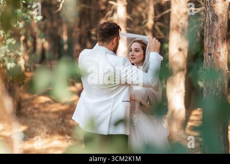 Der Bräutigam hebt den Schleier der Bräute während der Hochzeitszeremonie im Wald. Hochwertige Fotos Stockfoto