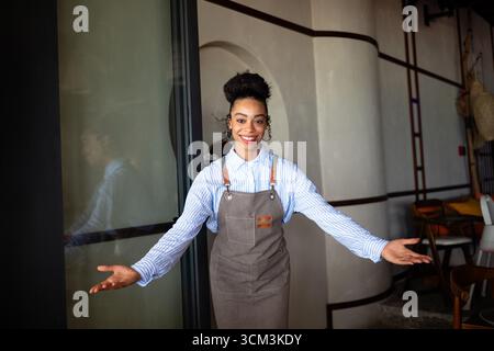 Selbstbewusstes Café, Restaurantbesitzer, der mit überkreuzten Armen steht und Gäste im Coffee Shop begrüßt Stockfoto