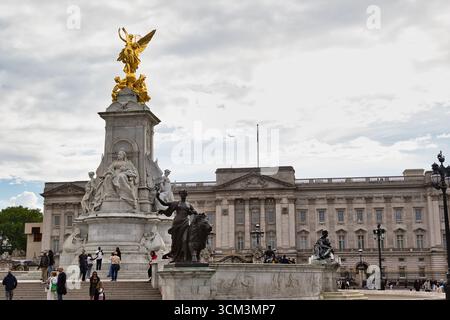 Eine breite Aufnahme des Victoria Memorial vor dem Buckingham Palace, mit einem großen Marmormonument, gekrönt von einer goldenen Statue, mit Menschen versammelt Stockfoto
