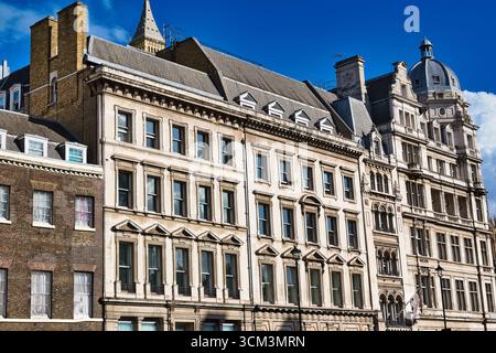 Ein Blick nach oben auf verzierte, mehrstöckige Gebäude unter einem hellblauen Himmel. Die Architektur verfügt über verschiedene Steinfassaden, zahlreiche Fenster und Dekorationen Stockfoto