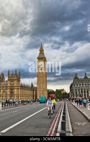 Ein Blick auf Big Ben und die Houses of Parliament in London mit bewölktem Himmel, eine Straße mit Radfahrern, Fußgängern und Fahrzeugen in London, Großbritannien. Stockfoto