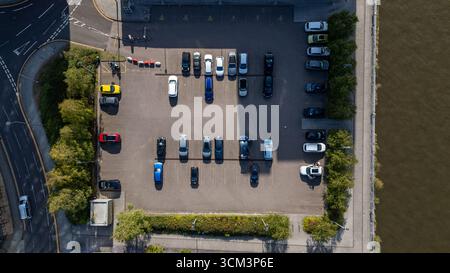 Ein Blick aus der Vogelperspektive auf einen Parkplatz neben einem Gewässer, gefüllt mit geparkten Autos und umgeben von Bäumen und Vegetation in Newcastle upon Tyne, Großbritannien. Stockfoto