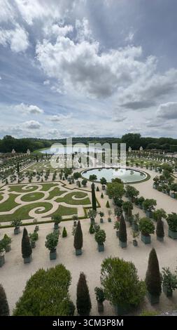 Ein Blick aus der Vogelperspektive zeigt einen sorgfältig gepflegten Garten mit geometrischen Rasenflächen, einem runden Teich und zahlreichen Topfbäumen. Stockfoto