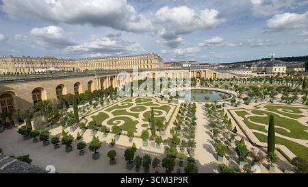Die weitläufigen Gärten von Versailles mit sorgfältig gepflegten Rasenflächen, einem runden Teich und Reihen von Topfbäumen sind aus der Vogelperspektive zu sehen Stockfoto