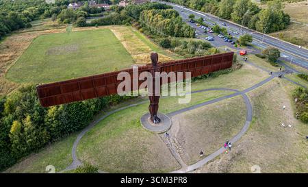 Eine aus verwittertem Stahl gefertigte Skulptur des Angels des Nordens aus der Vogelperspektive erhebt sich deutlich auf einem grasbewachsenen Hügel mit Wegen, die zu ihm führen, einer Straße W Stockfoto
