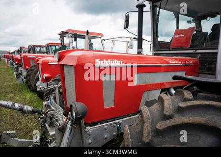 Logo und Beschilderung auf der Motorhaube eines roten Schlüter-Traktors vor anderen historischen Schlüter-Lkw, Hallbergmoos, Bayern, Deutschland Stockfoto
