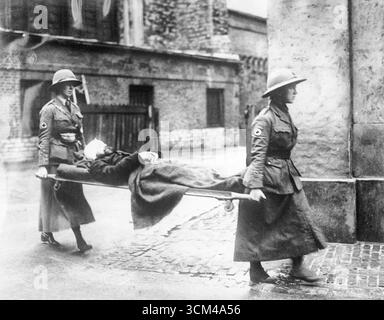 Zwei britische Bahrenträgerinnen in Militäruniform mit einem verwundeten belgischen Soldaten während des Ersten Weltkriegs, was die wichtige Rolle der Frauen bei der medizinischen Evakuierung an vorderster Front unterstreicht Stockfoto
