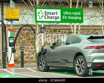 Bridgend, Wales, Vereinigtes Königreich - 26. März 2025: Auto in einer Parkbucht an ein Terminal zum Aufladen von Elektrofahrzeugen in einem Supermarkt angeschlossen. Keine Personen. Stockfoto