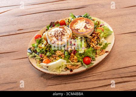 Warmer, geschmolzener Ziegenkäsesalat auf einem Eichenblatt-Salatbett, geröstete Kirschtomaten und knusprige Roggenbrotcroutons Stockfoto