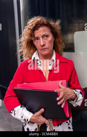 Geschäftsfrau mit Akten, die auf der Straße besorgt aussieht Stockfoto
