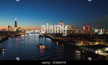 Aus der Vogelperspektive der beleuchteten Londoner Stadtlandschaft, die sich in der Abenddämmerung auf der Themse spiegelt, mit Tower Bridge, The Shard und anderen Sehenswürdigkeiten, die eine atemberaubende Stadtnächtlichkeit schaffen. Drohnenflug Stockfoto