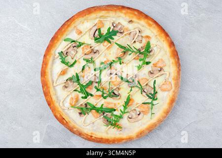 Weiße Sauce Pizza mit Huhn, Pilzen, Rucola und getrizzled Dressing auf knusprigem Kruste über grauem Stein Hintergrund Stockfoto