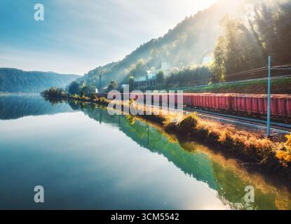 Luftaufnahme des roten Güterzuges, der sich in der Nähe des Sees in Bergen bewegt Stockfoto