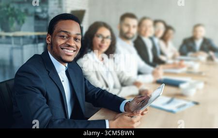 Afrikanischer Geschäftsmann Bei Einem Corporate Meeting Mit Kollegen, Die Im Büro Sitzen Stockfoto