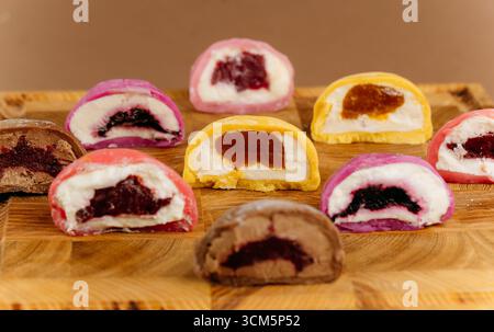 Verschiedene bunte Mochi-Eishälften auf Holzbrett, Nahaufnahme, Studiobeleuchtung Stockfoto
