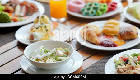 Abwechslungsreiches Frühstücksbuffet auf Holztisch mit Eiern benedict, Stockfoto