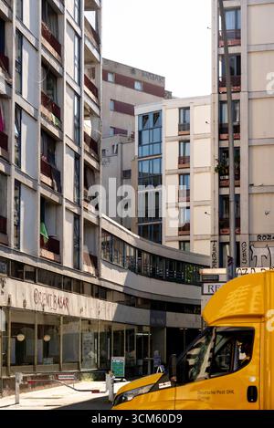 Eine lebendige, düstere Straßenszene am Berliner Kottbusser Tor. Ein gelber Lieferwagen verleiht dem dichten, mit Graffiti bedeckten sozialen Haus einen Farbakzent Stockfoto