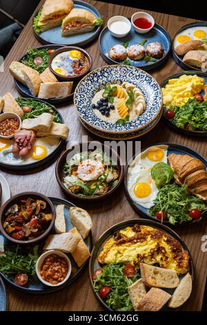 Köstliche Auswahl an Gourmet-Frühstücksgerichten, die auf Holztisch in einem gemütlichen Restaurant serviert werden Stockfoto