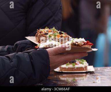 Frisch zubereitete Sandwiches mit offenem Gesicht, Fleisch, Käse und Gemüse, serviert auf einem Papiertablett auf dem Bauernmarkt von Naplavka in Prag. Stockfoto