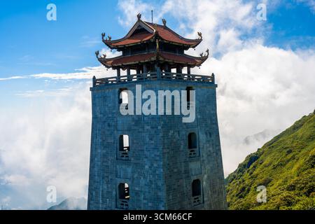 Ein traditioneller Stein-Pagode-Turm erhebt sich über den Wolken auf dem Fansipan-Berg in Sapa, Provinz Lao Cai, Vietnam. Stockfoto