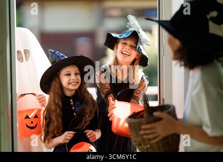 Glückliche Leute feiern Halloween. Erwachsene behandelt Kinder im Freien mit Süßigkeiten. Stockfoto