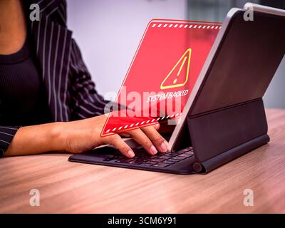 Geschäftsfrau, die einen digitalen Tablet-Computer mit rotem Warnbildschirm verwendet, der die Warnung „System gehackt“ anzeigt, symbolisiert Cybersicherheitsverletzungen und Hackerangriffe Stockfoto