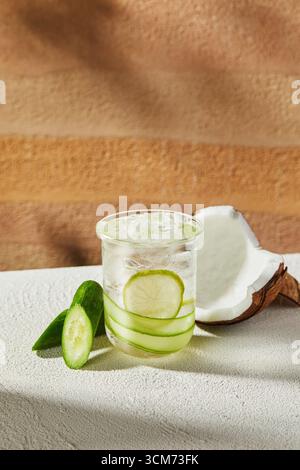 Erfrischendes Gurke Lime Kokoswasser-Getränk im Glas, Kokoswasser mit Gurke und Eiswürfeln auf weißem Tisch Stockfoto