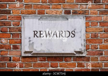 Geschäfts- und Risiko- oder Vergütungskonzept. Kopierbereich. BELOHNUNGEN auf einer Tafel an einer verwitterten Ziegelwand. Stockfoto
