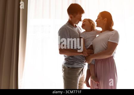 Glückliche Familie, die intime Momente am Fenster genießt Stockfoto