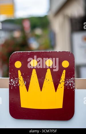 Spiez, Swtizerland - 11. September 2025: Ein verwittertes Schild mit gelbem Kronensymbol auf rotem Hintergrund. Stockfoto