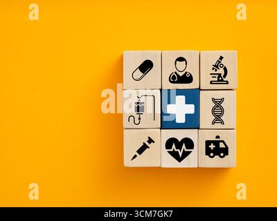 Gesundheits- und Medizinkonzept mit Ikonen auf Holzwürfeln, die in einem Quadrat auf gelbem Hintergrund angeordnet sind Stockfoto
