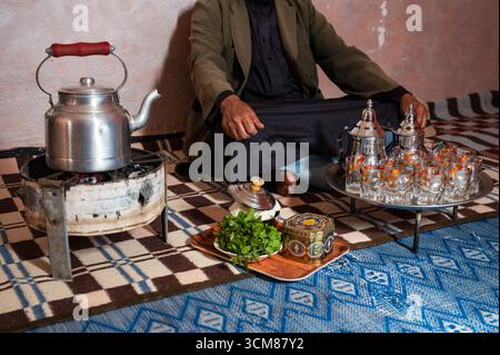 Marokkanischer Mann vor dem Tee-Set mit Wasserkocher und Gläsern. Stockfoto
