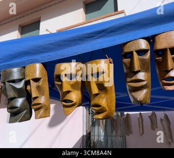 Handgeschnitzte Holzmasken sardischer Tradition unter blauem Baldachin Stockfoto