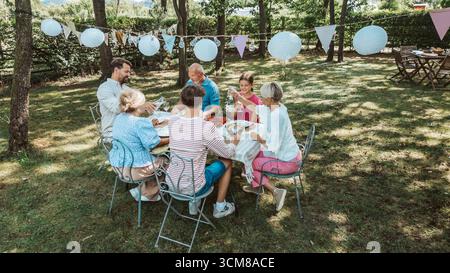Luftaufnahme von Familientreffen zum Grillen im Sommergarten, Reden und Essen gegrillter Speisen. Stockfoto