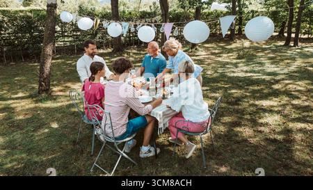 Luftaufnahme von Familientreffen zum Grillen im Sommergarten, Reden und Essen gegrillter Speisen. Stockfoto