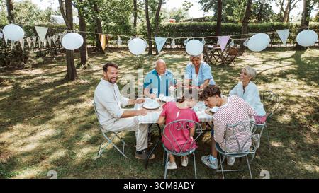 Luftaufnahme von Familientreffen zum Grillen im Sommergarten, Reden und Essen gegrillter Speisen. Stockfoto