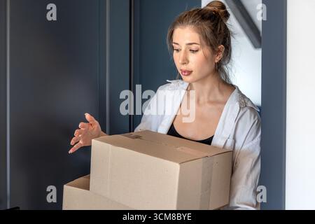 Junge Frau mit Kisten im Eingang, fokussierter Look. Eine Person. Stockfoto