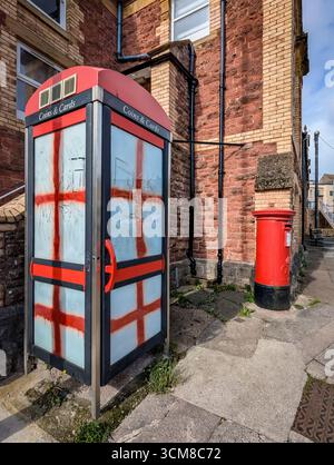 Paignton, Großbritannien. September 2025. Traditionelle rote Telefonbox mit Fenstern, die mit Graffiti der rot-weißen Flagge von St. George, der Nationalflagge Englands, bedeckt sind. Autor: Thomas Faull/Alamy Live News Stockfoto