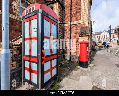 Paignton, Großbritannien. September 2025. Traditionelle rote Telefonbox mit Fenstern, die mit Graffiti der rot-weißen Flagge von St. George, der Nationalflagge Englands, bedeckt sind. Autor: Thomas Faull/Alamy Live News Stockfoto