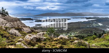 Eine malerische Landschaft mit einem Panoramablick auf üppige Hügel, ruhige Seen und verstreute Inseln unter einem dramatischen bewölkten Himmel, die essen einfangen Stockfoto