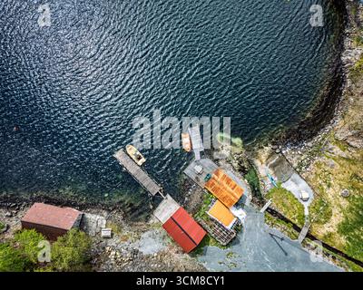 Eine hohe Aussicht auf kleine Docks, Boote und pulsierende Bootshäuser entlang einer malerischen Küste. Stockfoto