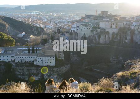 Panoramablick auf eine felsige Klippe mit einer historischen Stadt im Hintergrund bei Sonnenuntergang, wo drei Personen die Landschaft genießen. Perfekt für Naturthemen. Stockfoto