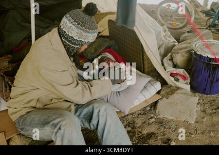 Obdachloser kaukasischer Mann tröstet den verletzten Schwarzen Mann im Außenlager Stockfoto