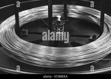 Metalldraht auf einer Spule in einer Industriemaschine und wird zur Herstellung von Metallteilen von Gegenständen verwendet. Stockfoto